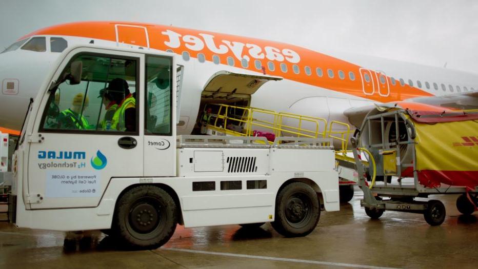 Baggage tractor and luggage cart in front of easyJet aeroplane.